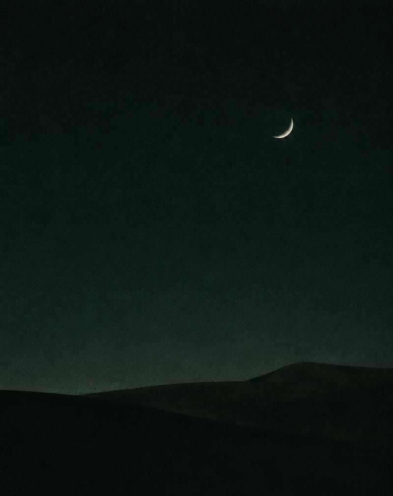 fin croissant de lune au-dessus de dunes sombres